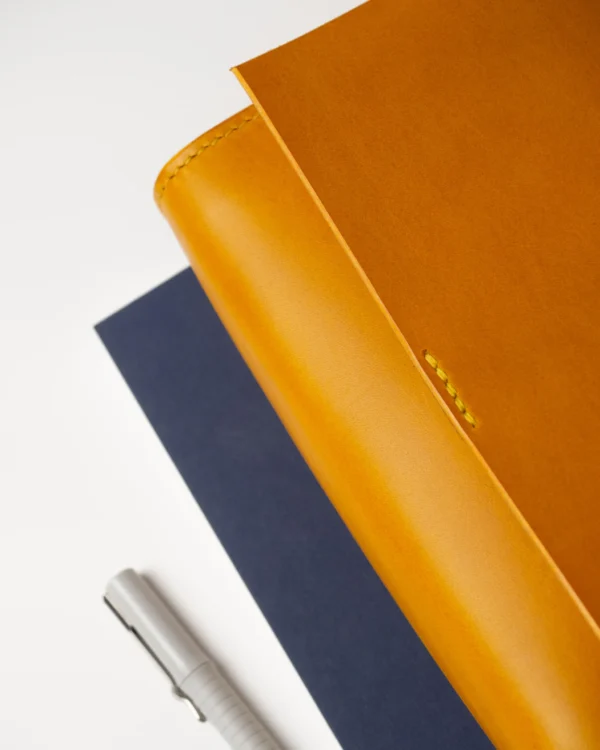 torebka-nr1-habaz-musztardowa-detal-struktura-koloru Abstrakcyjny detal struktury i koloru skórzanej torebki Habaż w zestawieniu z granatowym papierem.