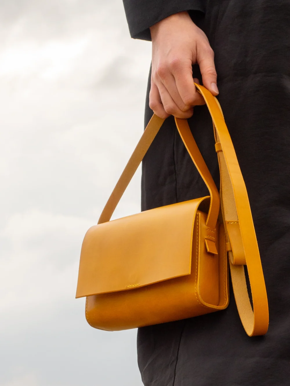 torebka-nr1-habaz-musztardowa-stylizacja-trzymana-za-pasek Detal skórzanej torebki Habaż trzymanej za pasek, podkreślający jakość skóry i szwów.