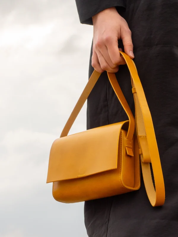 torebka-nr1-habaz-musztardowa-stylizacja-trzymana-za-pasek Detal skórzanej torebki Habaż trzymanej za pasek, podkreślający jakość skóry i szwów.