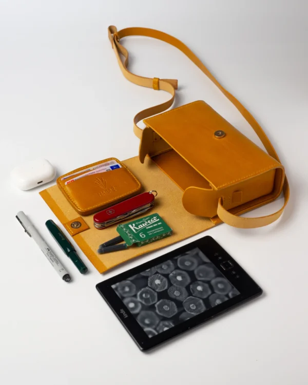 torebka-nr1-habaz-musztardowa-widok-edc-akcesoria Skórzana torebka musztardowa Habaż otwarta, z widocznym portfelem, Kindle i akcesoriami EDC.
