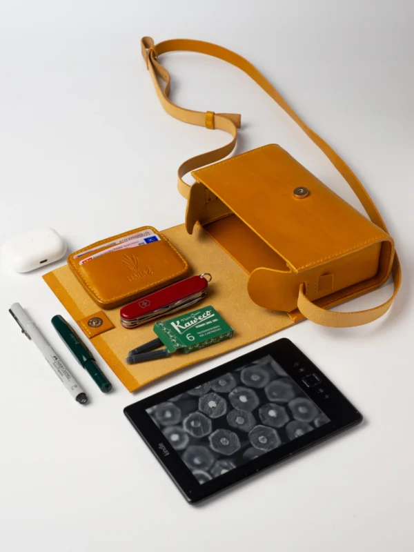 Skórzana torebka musztardowa Habaż otwarta, z widocznym portfelem, Kindle i akcesoriami EDC.