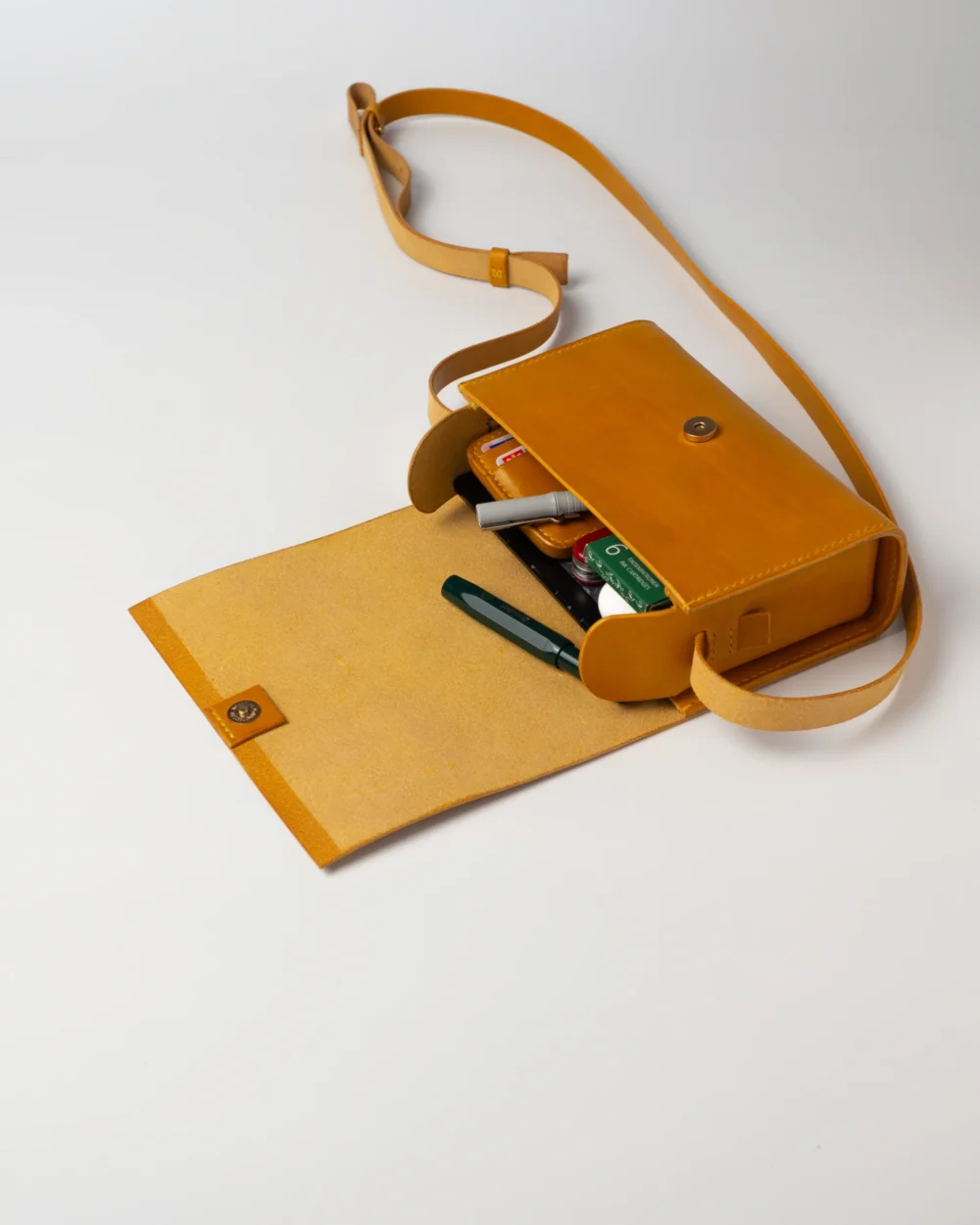 torebka-nr1-habaz-musztardowa-wnętrze-z-piórem Musztardowa torebka Habaż otwarta, z widocznymi w środku długopisami i wkładami do pióra wiecznego.