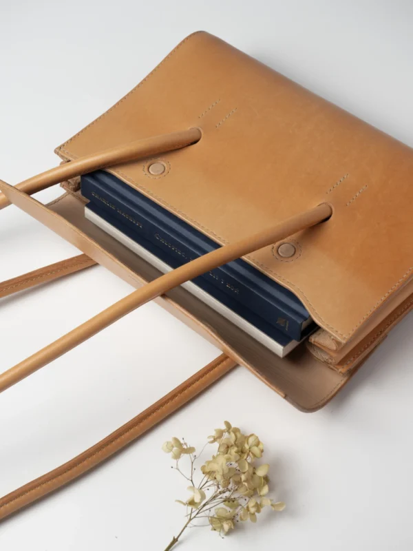 Wnętrze naturalnej torebki Habaż z widocznymi włożonymi notesami i suszonym kwiatem.