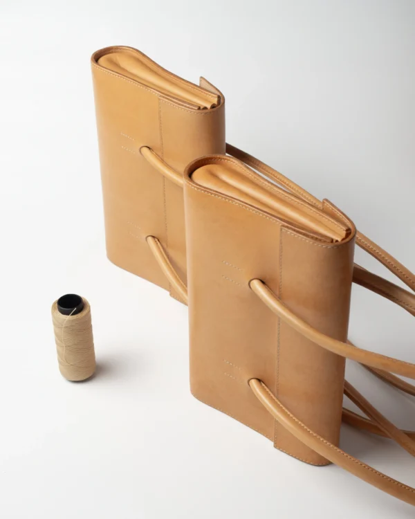 torebka-nr2-habaz-naturalna-produktowe-dwie-sztuki-nić Dwie naturalne torebki Habaż stojące obok szpulki z żółtą nicią kaletniczą.