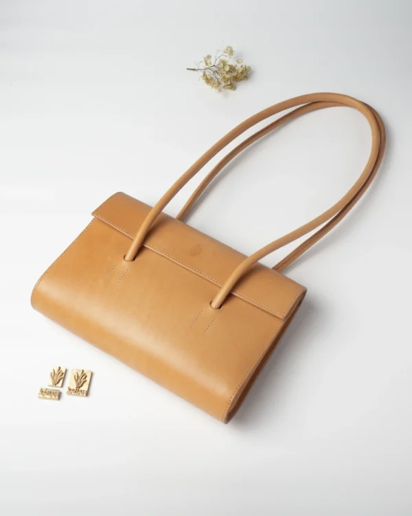 torebka-nr2-habaz-naturalna-produktowe-stempel Naturalna torebka Habaż na ramieniu leżąca na białym tle obok stempli z logo.