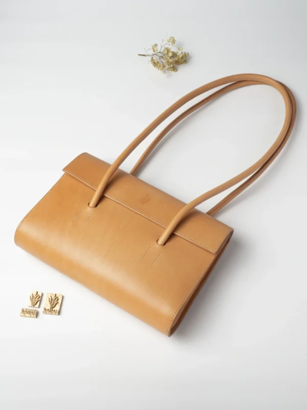 Naturalna torebka Habaż na ramieniu leżąca na białym tle obok stempli z logo.