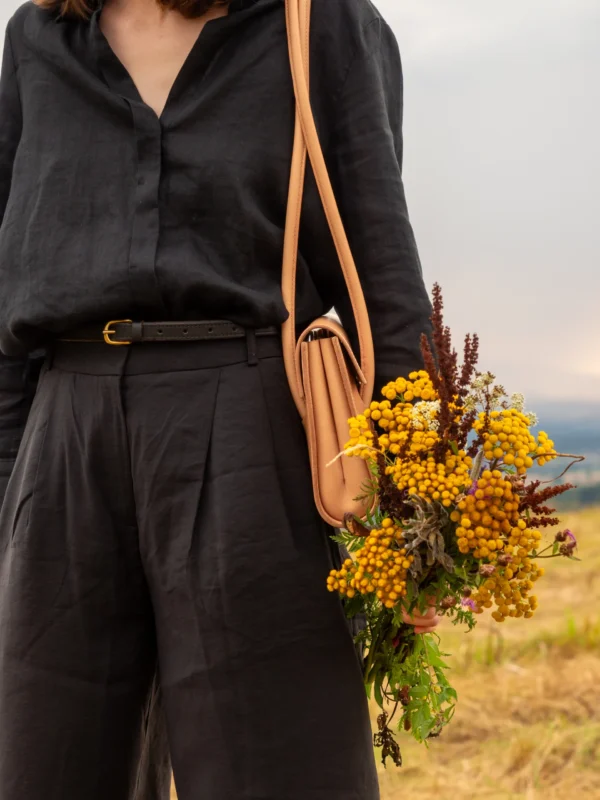 torebka-nr2-habaz-naturalna-stylizacja-kwiaty Detal naturalnej torebki Habaż na ramieniu i dłoń trzymająca bukiet żółtej wrotyczy.