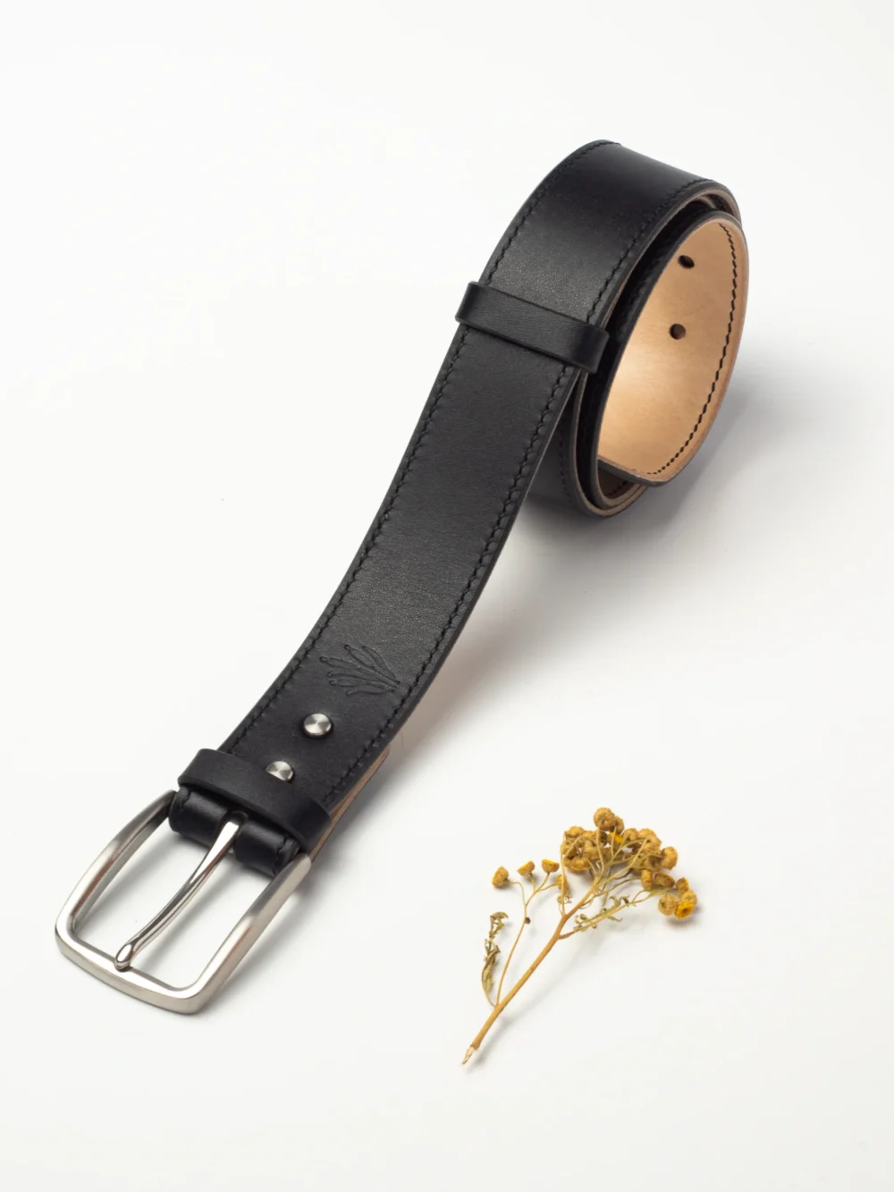 pasek-buttero-habaz-czarny-glowny-stal Skórzany pasek Buttero w kolorze czarnym, zwinięty, z dużą klamrą ze stali nierdzewnej.