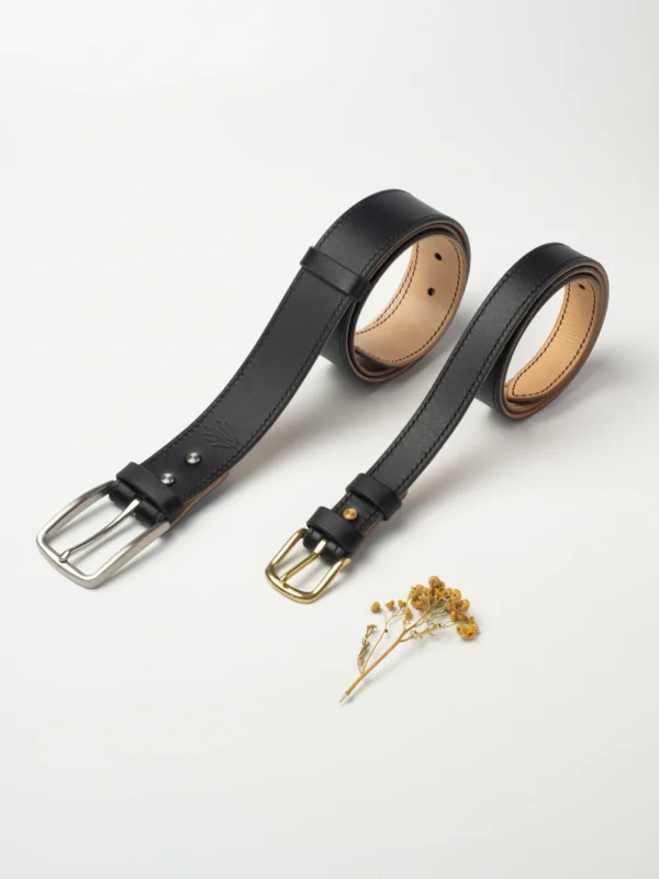 pasek-buttero-habaz-czarny-produkt-kontrast Dwa czarne paski Buttero różnej szerokości, jeden ze stalową, drugi z mosiężną klamrą.