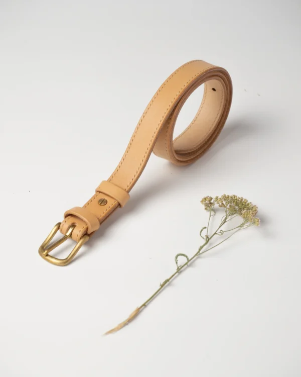 pasek-buttero-habaz-naturalny-produkt-zblizenie Skórzany pasek Buttero w kolorze naturalnym, zwinięty w spiralę, z widocznymi przeszyciami i mosiężną klamrą.
