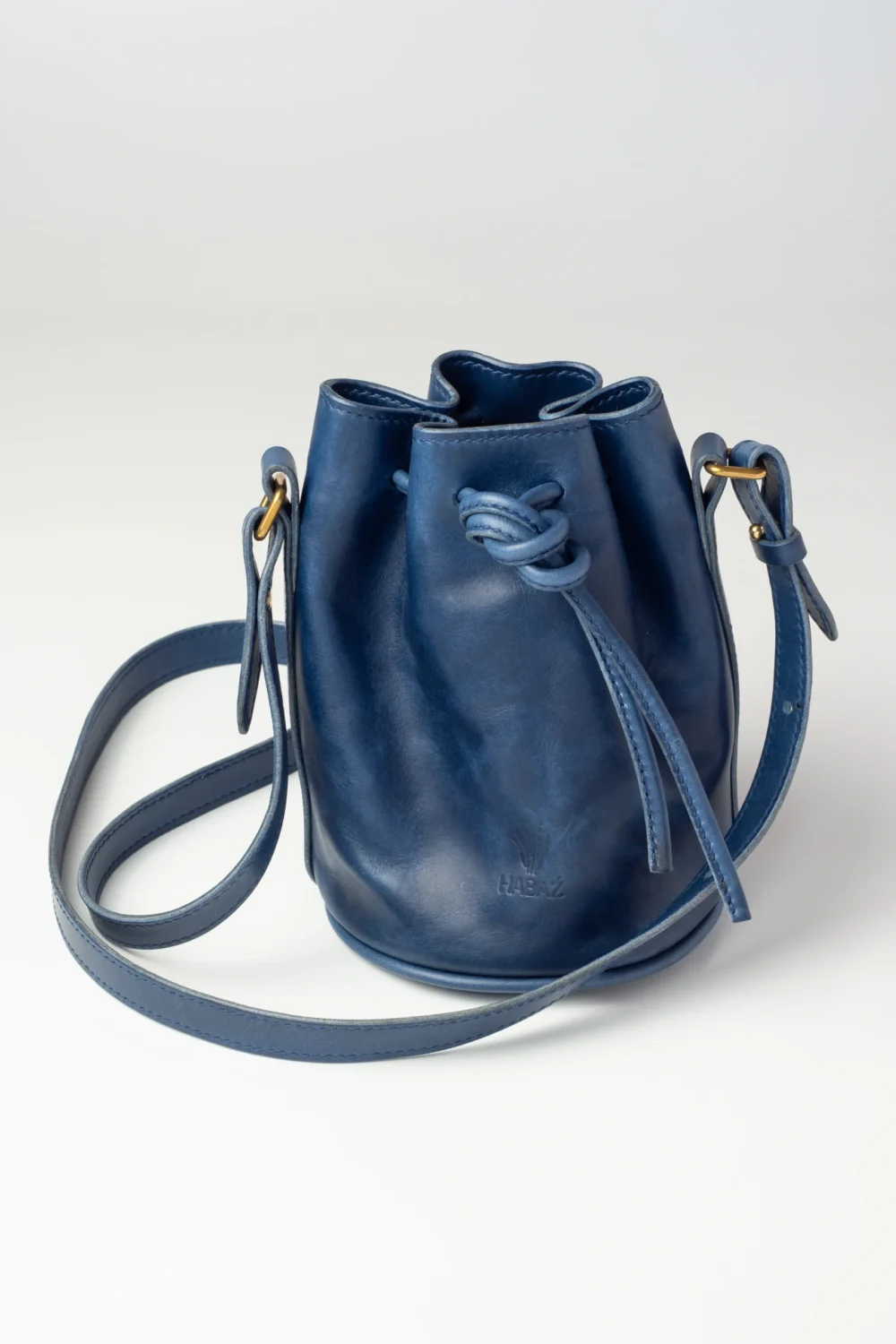 Skórzana torebka-worek Habaż w kolorze chabrowym z zawiązanym sznurkiem na ramię.