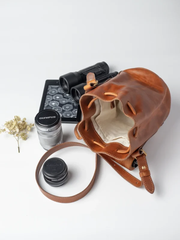 Karmelowa torebka Habaż, e-czytnik, lornetka i obiektyw na białym tle.