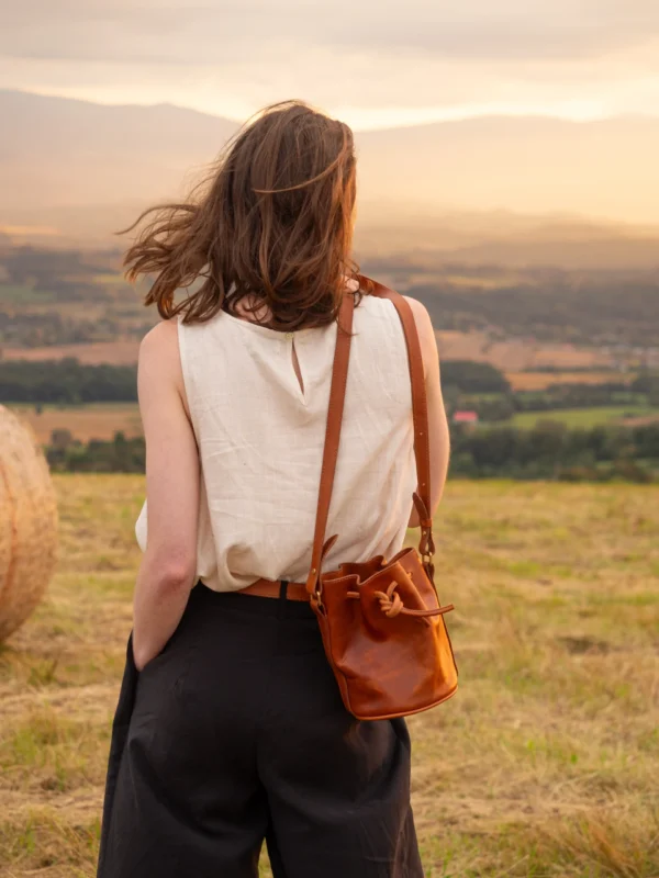 torebka-nr3-habaz-karmelowa-stylizacja-z-tyłu-zachód-słońca Kobieta z karmelową torebką Habaż (typu worek) na ramieniu, patrząca na zachód słońca.