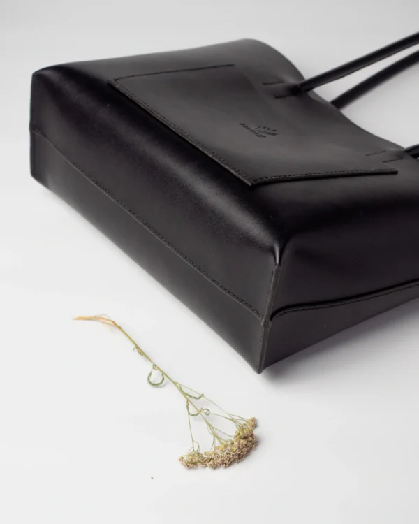 torebka-nr4-habaz-czarny-detal-szycie Zbliżenie na dolny róg i boczną krawędź czarnej torebki Shopper, widoczne precyzyjne szycie.