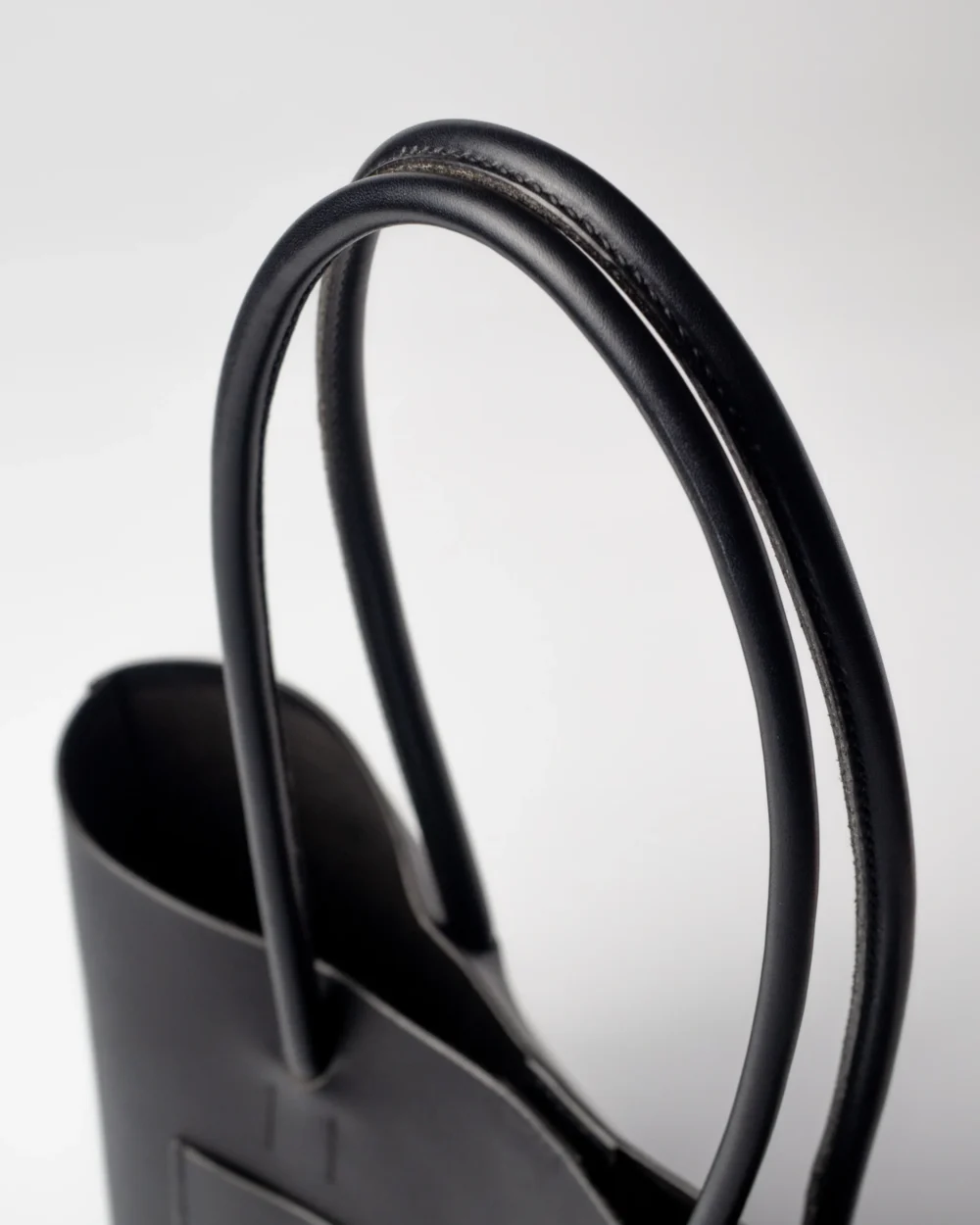 Zbliżenie na podwójne, skórzane rączki torebki Shopper, z widoczną fakturą skóry.