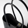 torebka-nr4-habaz-czarny-detal-zatrzask Zbliżenie na czarne skórzane uchwyty torebki Shopper i złoty zatrzask magnetyczny na środku.