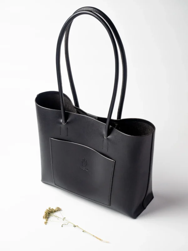 Czarna skórzana torebka Shopper na białym tle, widok z przodu, widoczna zewnętrzna kieszeń.