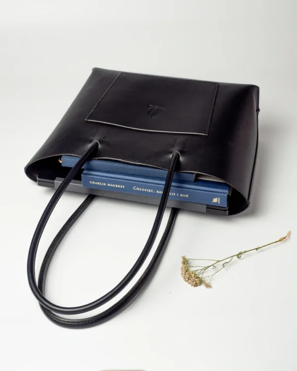 torebka-nr4-habaz-czarny-wnetrze-ksiazki Widok z góry na otwartą, czarną torebkę Shopper, w której widać dwie niebieskie książki.