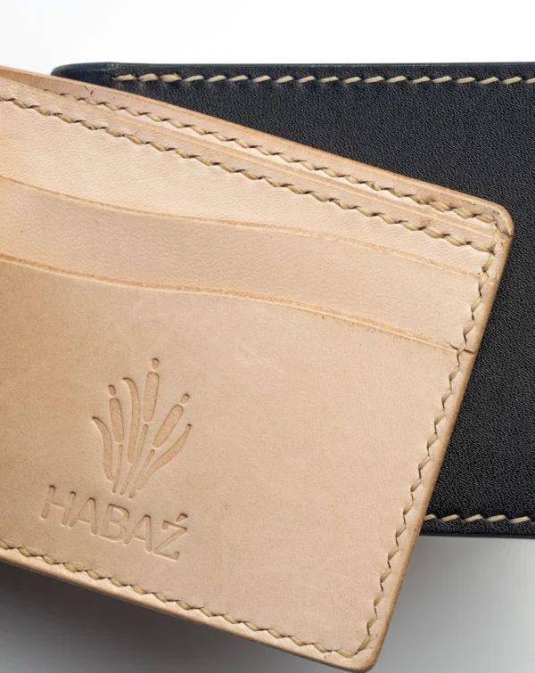 portfel-habaz-wnętrze-logo-kieszonka-czarne-tło Zbliżenie na beżowe, naturalne wnętrze portfela Habaź z tłoczonym logo i kieszonkami na karty, na tle czarnej skóry.